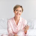 happy-woman-sitting-in-bed-using-cell-phone-2022-01-19-00-11-50-utc-e1659175295343.jpg